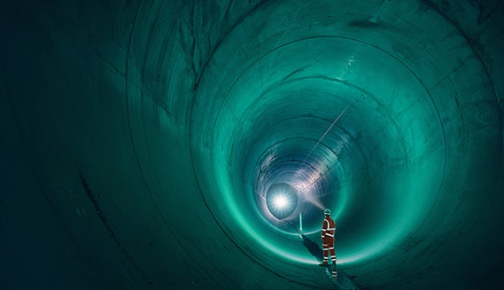 Person in hi-vis overalls standing inside of a large tunnel